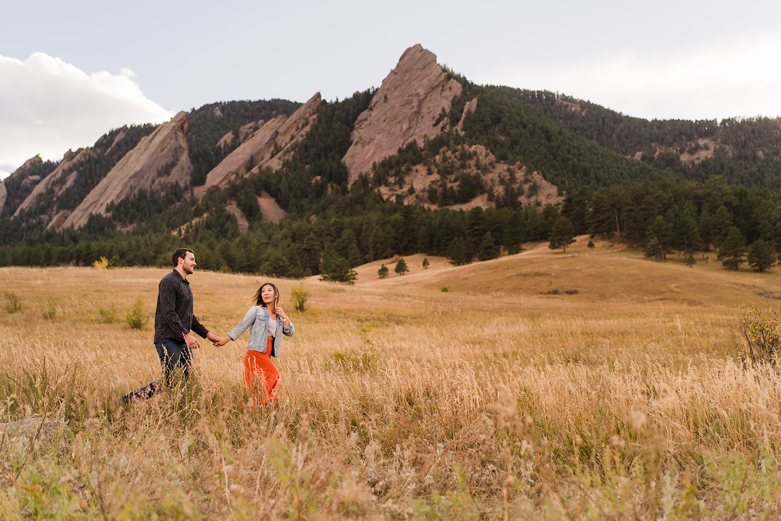 Engaged couple walking through Chautauqua Park during golden hour in Boulder.