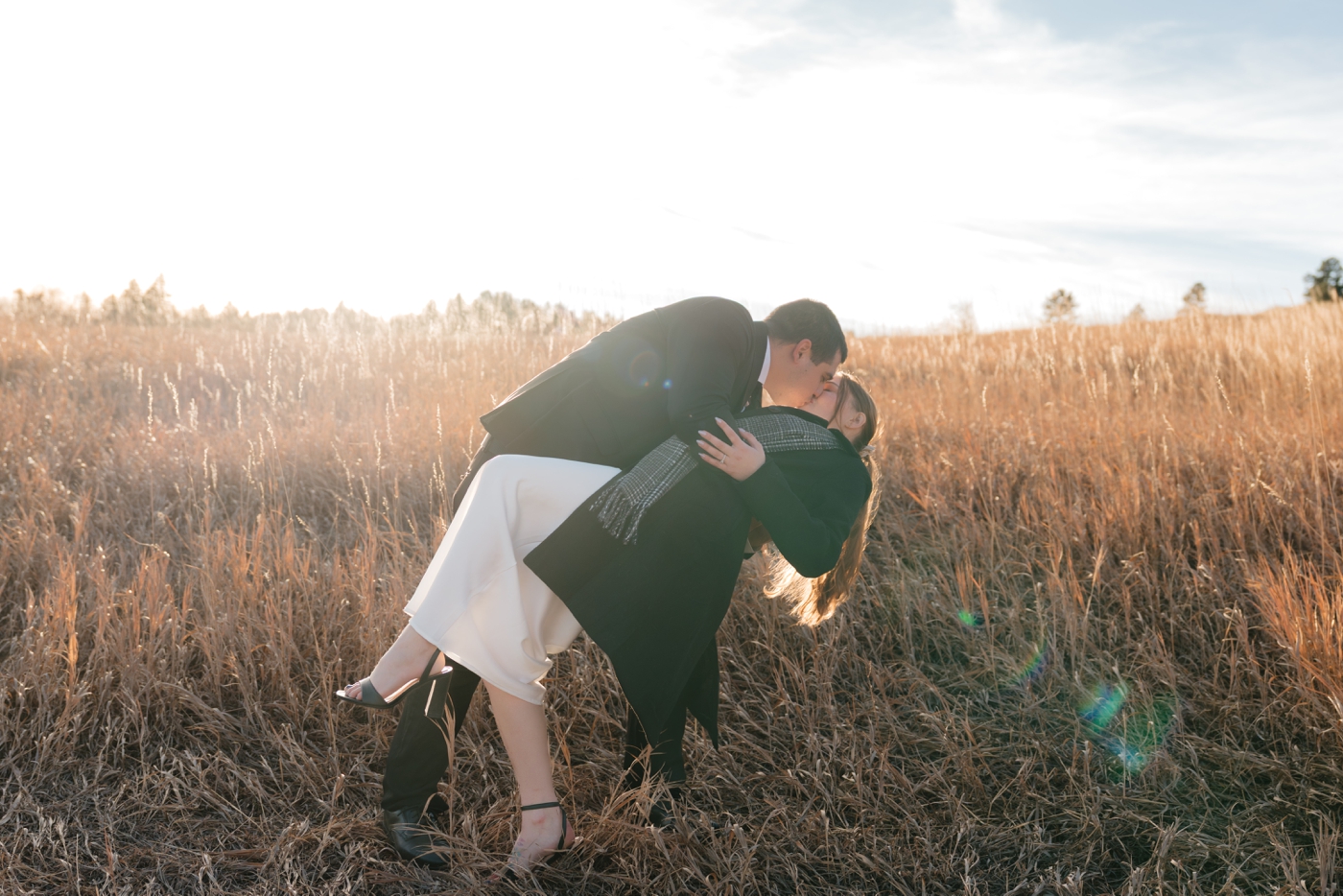 Groom dipping bride for a kiss in golden field