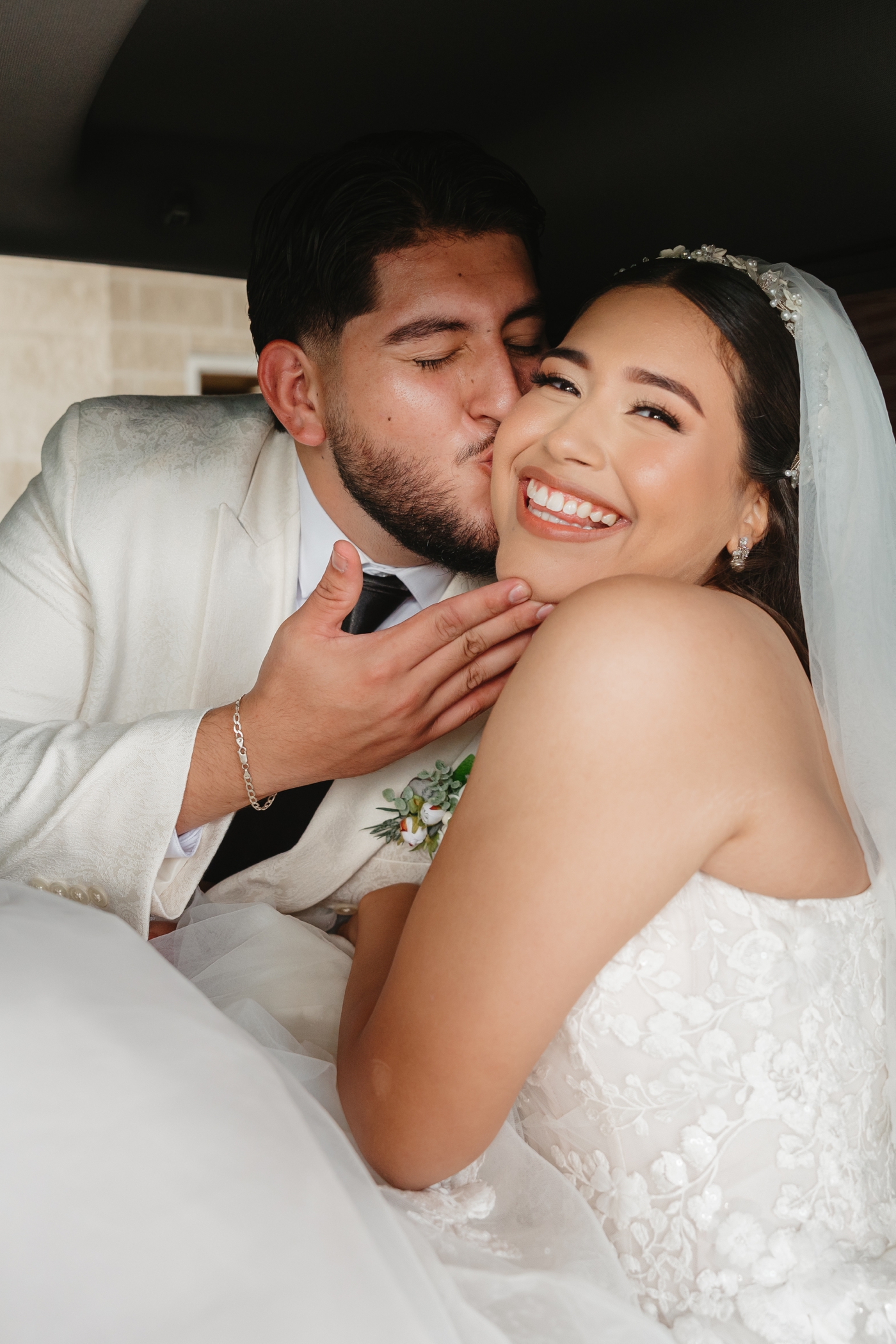 Groom kissing bride on the cheek and displaying wedding ring after ceremony
